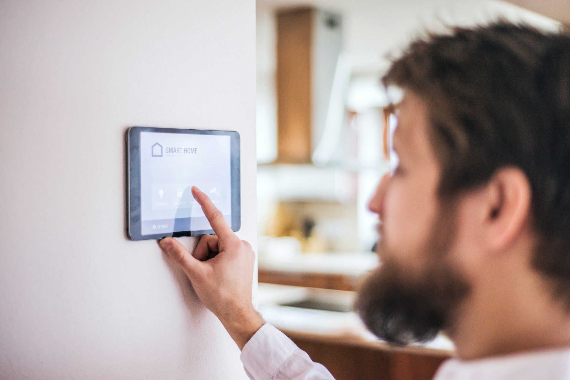 A man adjusts the temperature on an electronic device, showcasing modern technology in climate control.