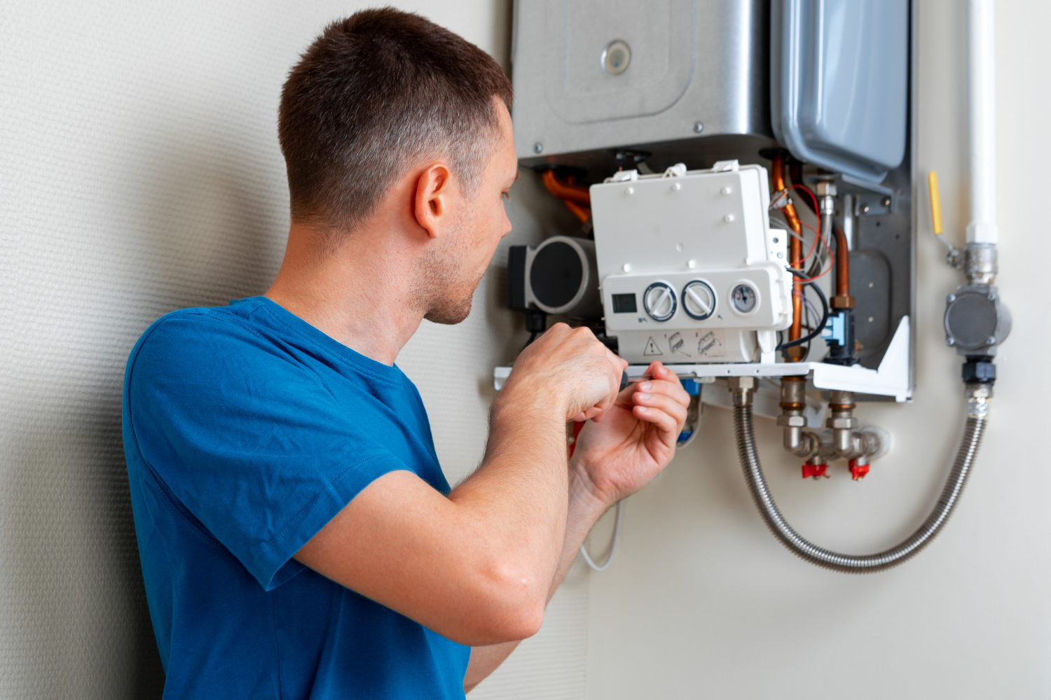 A technician repairs a gas boiler in a well-lit room, focusing on the intricate components of the appliance.